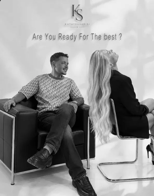 Siyah-beyaz kampanya görseli: “Are You Ready For The Best?” yazısı altında koltukta oturan bir erkek ve uzun, dalgalı sarı saçlı bir kadın
